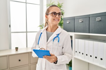 Poster - Young blonde woman wearing doctor uniform using touchpad working at clinic