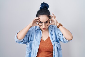 Canvas Print - Young modern girl with blue hair standing over white background trying to open eyes with fingers, sleepy and tired for morning fatigue