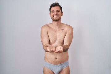 Sticker - Young hispanic man standing shirtless wearing underware smiling with hands palms together receiving or giving gesture. hold and protection