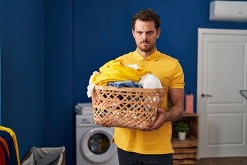 Sticker - Young hispanic man holding laundry basket skeptic and nervous, frowning upset because of problem. negative person.