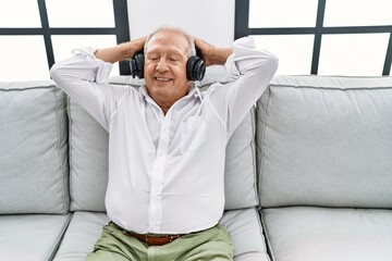 Canvas Print - Senior man listening to music sitting on sofa at home