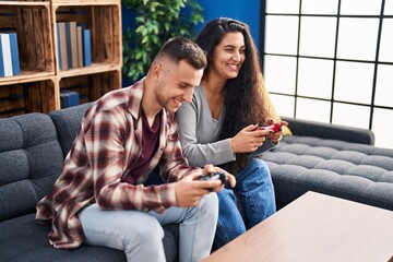 Poster - Man and woman couple playing video game sitting on sofa at home