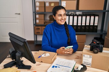 Poster - Young hispanic woman ecommerce business worker using smartphone at office