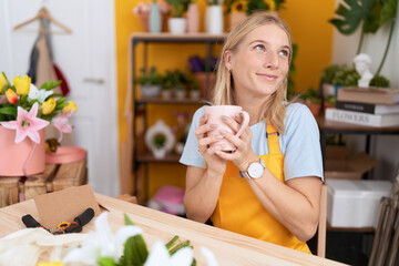 Canvas Print - Young blonde woman florist smiling confident drinking cup of coffee at flower shop