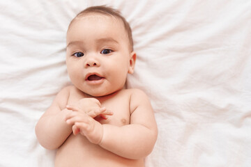 Sticker - Adorable hispanic toddler smiling confident lying on bed at bedroom