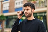 Fototapeta Miasto - Young arab man listening audio message by the smartphone at street