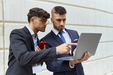 Wall Mural - Two hispanic men business workers using laptop and smartphone over isolated white background