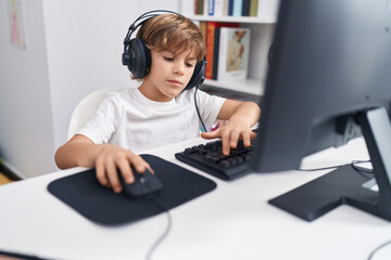 Poster - Adorable caucasian boy student using computer sitting on table at classroom