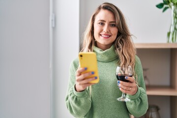 Sticker - Young woman using smartphone drinking wine at home