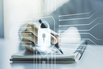 Double exposure of creative lock hologram with chip and man hand writing in notebook on background. Information security concept