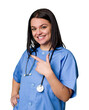 Young nurse woman isolated smiling and pointing aside, showing something at blank space.