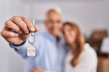 Poster - Middle age man and woman couple hugging each other holding key of new house at new home