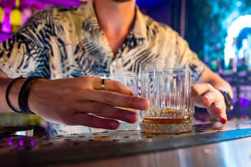 Wall Mural - Bartender hand pouring whiskey on glass in bar