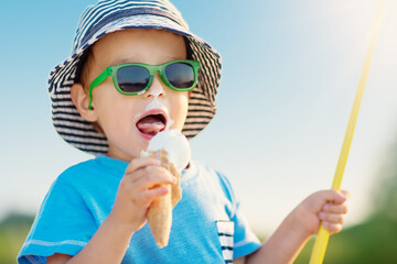 Little boy eating ice cream in sunny day in nature.