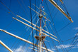 Sailing ship mast with rigging and cables against the sky.