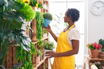 Canvas Print - Middle age african american woman florist holding plant at street