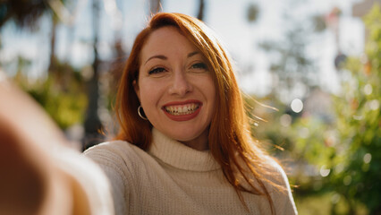 Wall Mural - Young redhead woman smiling confident make selfie by the camera at park