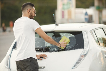 Indian man washing his white transportation on car wash