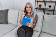 © Krakenimages.com - Middle age grey-haired woman smiling confident using touchpad and talking on the smartphone at home