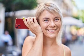 Poster - Young blonde woman miling confident listening audio message by the smartphone at street