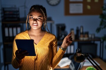 Canvas Print - African american woman with braids working at the office at night with tablet pointing aside worried and nervous with forefinger, concerned and surprised expression