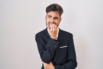 Sticker - Young hispanic man with tattoos wearing business suit and tie looking stressed and nervous with hands on mouth biting nails. anxiety problem.