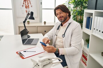 Canvas Print - Middle age man doctor using smartphone working at clinic