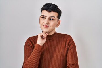 Canvas Print - Non binary person wearing make up standing over isolated background serious face thinking about question with hand on chin, thoughtful about confusing idea