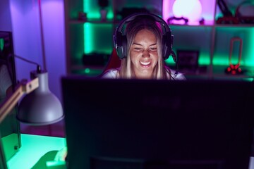 Poster - Young beautiful hispanic woman streamer playing video game using computer at gaming room