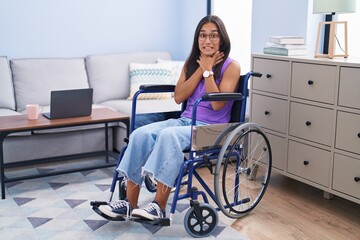 Wall Mural - Young hispanic woman sitting on wheelchair at home shouting and suffocate because painful strangle. health problem. asphyxiate and suicide concept.