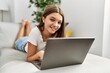 © Krakenimages.com - Adorable girl using laptop lying on sofa at home