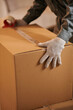 © DragonImages - Closeup image of mover sealing cardboard box with belongings of client