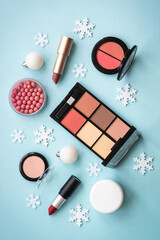 Wall Mural - Make up products and christmas decorations on blue background. Top view image with copy space.