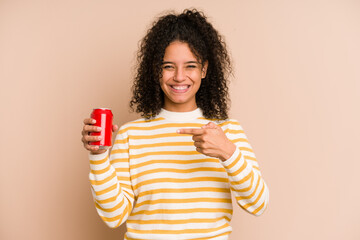 Young african american woman holding a cola refreshment isolated person pointing by hand to a shirt copy space, proud and confident