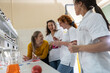 © BalanceFormCreative - Group of female chemistry scientists and students on coffee break. They're standing at the lap and chatting.