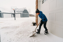 A child pushing a shovel hard to get snow off the ground. 