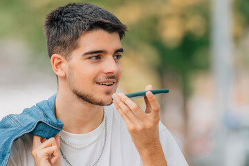 Wall Mural - young man on the street with phone sending voice message