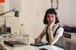 © Ana Luz Crespi/Stocksy - Tattoo artist at her office smiling