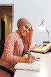 © VICTOR TORRES/Stocksy - Muslim worker writing in the agenda in modern office