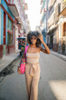 © Daniel Gonzalez/Stocksy - Cuban woman touching hair and walking on street