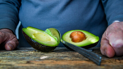 Wall Mural - Man holding avocado in rustic wooden table