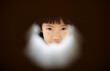 © ChaoShu Li/Stocksy - Asian girl looking at the camera through a hole in a building
