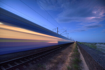 Wall Mural - high speed train in motion on the railway station at dusk. landscape with moving blue modern interci