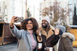 © Pedro Merino/Stocksy - Friends taking selfies while drinking hot chocolate at a winter market