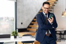 Portrait Of Handsome Businessman Using Smartphone In Modern Office