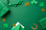 Fototapeta Kawa jest smaczna - Saint Patrick's Day concept. Top view photo of gift boxes gold coins bow-tie horseshoe envelope with letter and shamrocks on isolated green background with copyspace in the middle