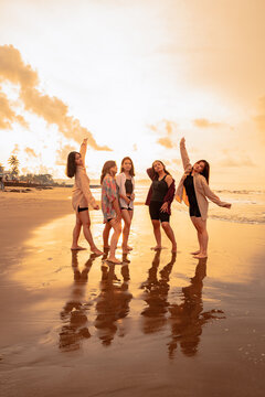 a group of asian women in shirts posing happily while visiting a beautiful beach