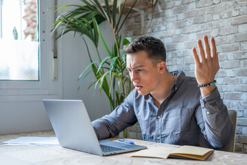 Unhappy young caucasian male worker in glasses look at laptop screen shocked by gadget breakdown or operational problems. Frustrated man confused surprised by unexpected error on computer device..