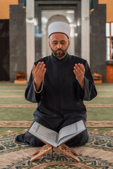 Canvas Print - A Muslim prayer man praying with hands up inside the mosque.