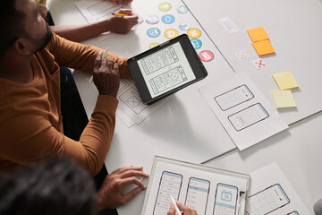 Wall Mural - group of ux designers discussing sketch of mobile application interface design and offering ideas